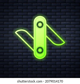Glowing neon Swiss army knife icon isolated on brick wall background. Multi-tool, multipurpose penknife. Multifunctional tool.  Vector