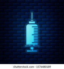 Glowing neon Syringe with pet vaccine icon isolated on brick wall background. Dog or cat paw print.  Vector Illustration