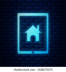 Glowing neon Tablet and smart home icon isolated on brick wall background. Remote control.  Vector Illustration