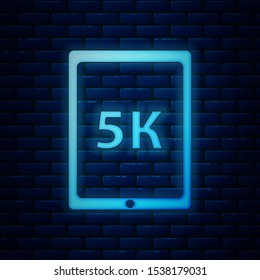 Glowing neon Tablet with text 5k icon isolated on brick wall background.  Vector Illustration