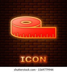Glowing neon Tape measure icon isolated on brick wall background. Measuring tape.  Vector Illustration