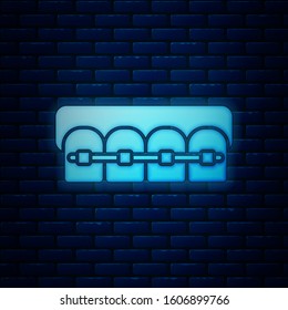 Glowing neon Teeth with braces icon isolated on brick wall background. Alignment of bite of teeth, dental row with with braces. Dental concept.  Vector Illustration