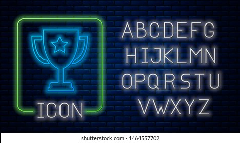 Glowing neon Trophy cup icon isolated on brick wall background. Award symbol. Champion cup icon. Neon light alphabet. Vector Illustration