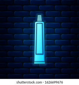 Glowing neon Tube of toothpaste icon isolated on brick wall background.  Vector Illustration