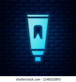 Glowing neon Tube of toothpaste icon isolated on brick wall background.  Vector Illustration