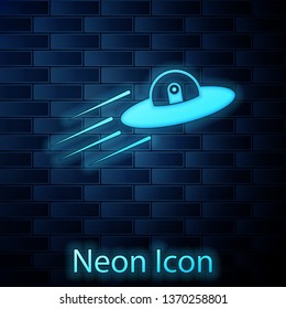 Glowing neon UFO flying spaceship and alien icon isolated on brick wall background. Flying saucer. Alien space ship. Futuristic unknown flying object. Vector Illustration
