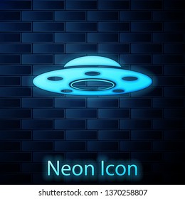 Glowing neon UFO flying spaceship icon isolated on brick wall background. Flying saucer. Alien space ship. Futuristic unknown flying object. Vector Illustration