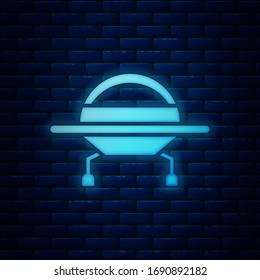 Glowing neon UFO flying spaceship icon isolated on brick wall background. Flying saucer. Alien space ship. Futuristic unknown flying object.  Vector Illustration