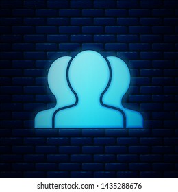 Glowing neon Users group icon isolated on brick wall background. Group of people icon. Business avatar symbol - users profile icon.  Vector Illustration
