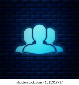Glowing neon Users group icon isolated on brick wall background. Group of people icon. Business avatar symbol users profile icon.  Vector Illustration