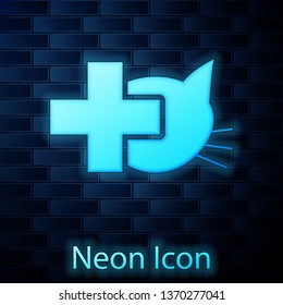 Glowing neon Veterinary clinic symbol icon isolated on brick wall background. Cross with cat veterinary care. Pet First Aid sign. Vector Illustration