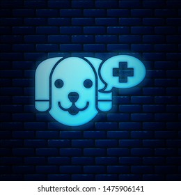 Glowing neon Veterinary clinic symbol icon isolated on brick wall background. Cross with dog veterinary care. Pet First Aid sign.  Vector Illustration