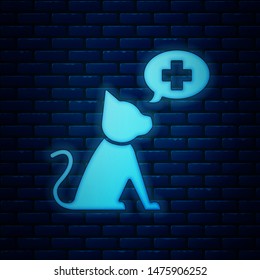 Glowing neon Veterinary clinic symbol icon isolated on brick wall background. Cross with cat veterinary care. Pet First Aid sign.  Vector Illustration