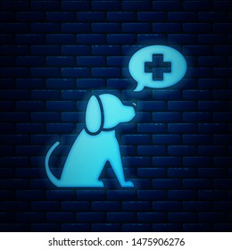 Glowing neon Veterinary clinic symbol icon isolated on brick wall background. Cross with dog veterinary care. Pet First Aid sign.  Vector Illustration