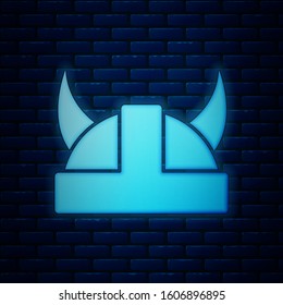 Glowing neon Viking in horned helmet icon isolated on brick wall background.  Vector Illustration