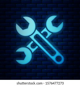 Glowing neon Wrench icon isolated on brick wall background. Spanner icon.  Vector Illustration