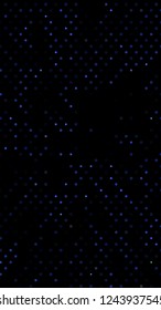 Glowing particles, polka dots on a dark blue background. Vertical festive banner. An elegant holiday pattern. Vector illustration.