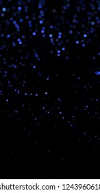 Glowing particles, polka dots on a dark blue background. Vertical festive banner. An elegant holiday pattern. Vector illustration.