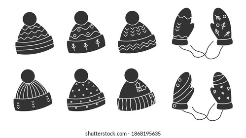 Glyph black knitted hats, mittens set. Cozy winter headwear with pom-pom. Seasonal xmas warm clothes. Hygge time, holiday cute accessory. Caps for cold season. Isolated on white vector illustration