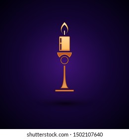Gold Burning candle in candlestick icon isolated on dark blue background. Old fashioned lit candle. Cylindrical candle stick with burning flame.  Vector Illustration