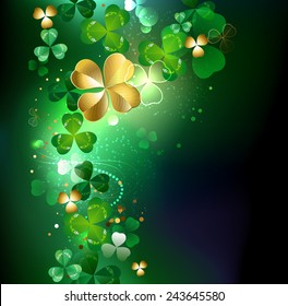 Gold clover with four leaves on dark glowing background. 