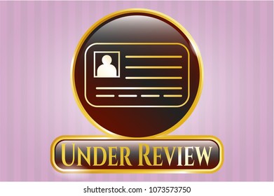   Gold emblem with identification card icon and Under Review text inside