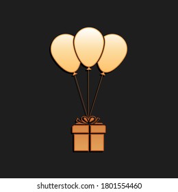 Gold Gift box with balloons icon isolated on black background. Long shadow style. Vector.