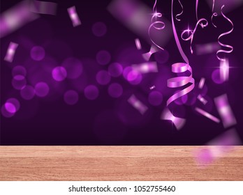 gold ribbons and confetti falling over wood table on violet  blurred background