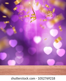 gold ribbons and confetti falling over wood table on violet  heart blurred background
