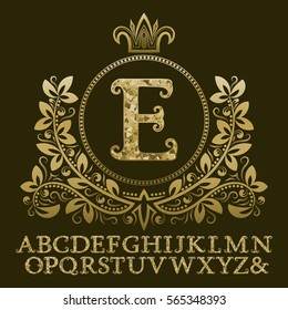 Golden encrusted letters and initial monogram in coat of arms form with crown. Royal font and elements kit for logo design.