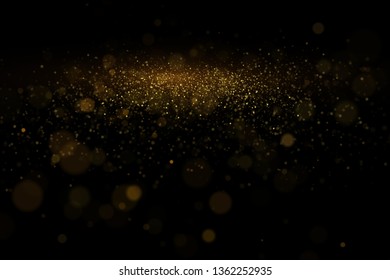 Golden glitter dust, glowing bokeh lights, shiny particles explosion on black background