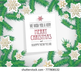 Golden paper snowflakes with Merry Christmas wishes and pine branches.