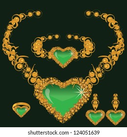 golden set from necklace ring earrings and bracelet with heart from green stone on dark background