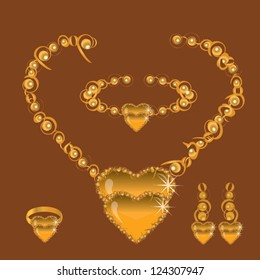 golden set from necklace ring earrings and bracelet with hearts orange stone on brown background