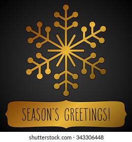 Golden snowflake and a frame with hand written season's greetings over black.