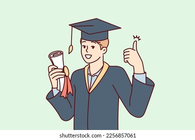 Graduate guy in academic gown and hat holds bundle with diploma and shows thumbs up. University student rejoices in getting quality education in good educational institution