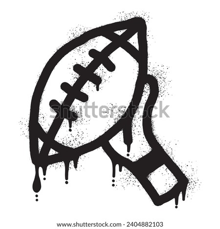 Graffiti of hands holding an American football ball with black spray paint
