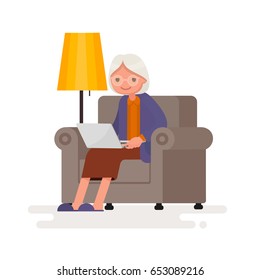 Grandmother with the computer sits in an armchair. Vector illustration in a flat style