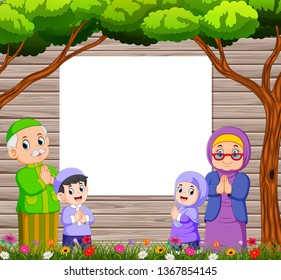 grandmother and grandfather with their grandchild are giving the greeting of ied mubarak near the blank board