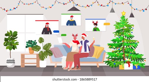 grandparents in festive hats discussing with children in masks during video call coronavirus quarantine concept new year christmas holidays celebration living room interior horizontal full length