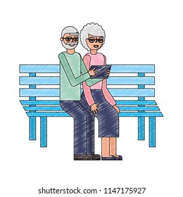 grandparents with tablet device sit in the bench