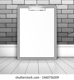 Gray clipboard with white blank paper stands near the brick wall on the boards. Mockup for design with shadow