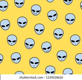 Gray faces of aliens on a yellow field. Decorative seamless pattern. Vector image. 
