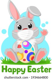 A gray rabbit in a medical mask with an Easter egg sits on the grass. Character, covid-19