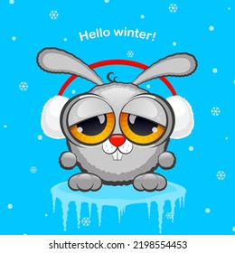 Gray rabbit in white fur headphones on a blue background with snow. The concept of winter, new year 