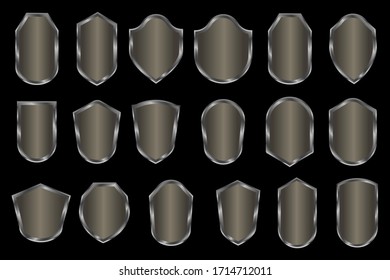 Escudos grises de tintes negros con un efecto metálico sin inscripciones sobre fondo negro. Escudos de varias formas con un diseño único. Gráficos vectoriales. Foto de stock.