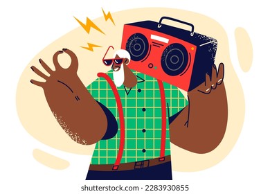 Gray-haired dark-skinned old man with tape recorder on shoulder smiles and shows OK gesture enjoy happy old age. elderly human wants to stay young and carries tape recorder to have retro party 