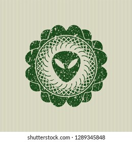 Green alien icon inside distress rubber stamp with grunge texture
