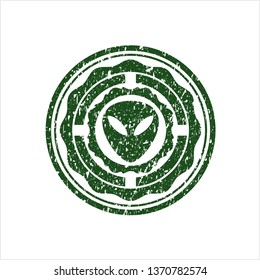Green alien icon inside distressed rubber stamp with grunge texture