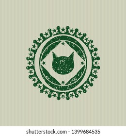 Green cat face icon inside rubber seal with grunge texture